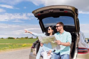 happy man and woman on road trip with rental car