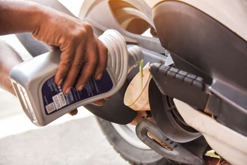 hand changing the oil on a motorcycle for maintance