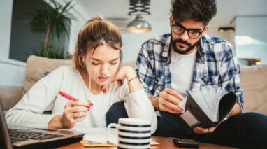 young couple filing 2020 taxes on their living room