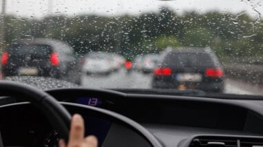 front view of traffic in rain from the inside drivers seat of a car