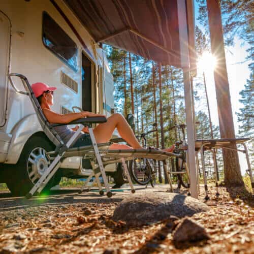 side view of woman in front of her camper in the woods