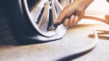 front view of hand filling a flat tire with air