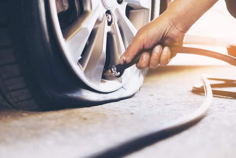 front view of hand filling a flat tire with air