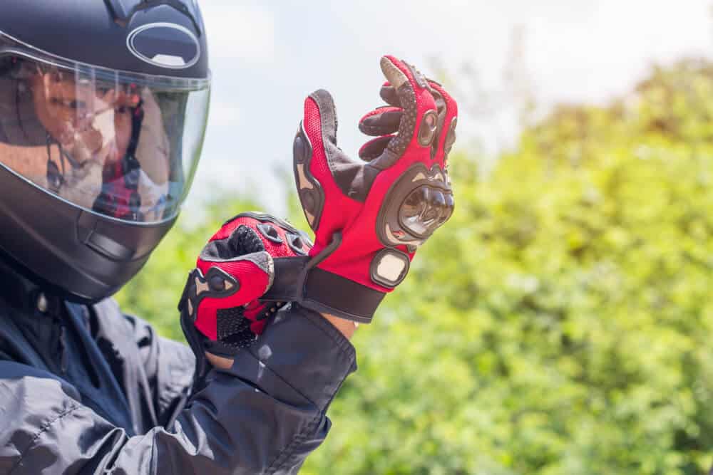 person with motorcycle helmet putting on riding gloves 