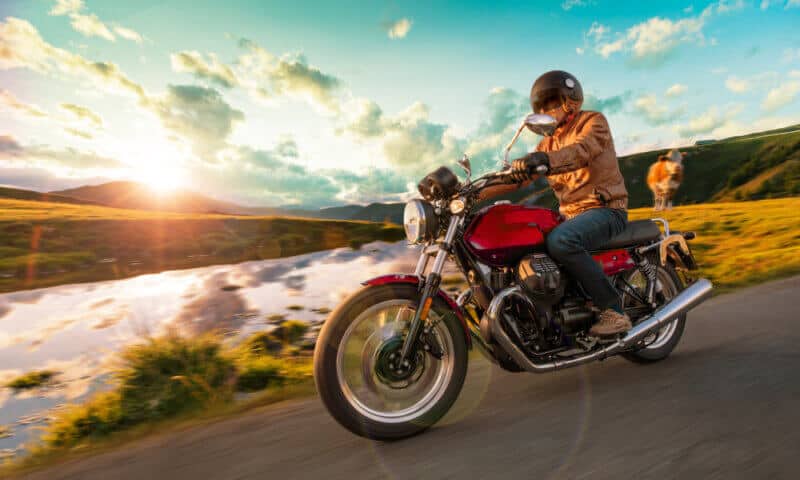 side view of a motorcycle rider on the road during a sunset
