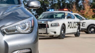 Two police vehicles stop a sedan on a routine traffic stop