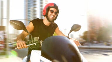 Portrait of handsome man on motorcycle ride in city smiling