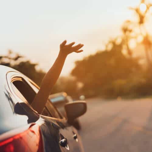 hand happily coming out or moving car window during a roadtrip