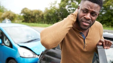 Male Motorist With Whiplash Injury In Car Crash Getting Out Of Vehicle