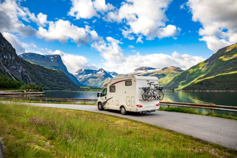 scenic view of a motorhome on a road with a lake in the background