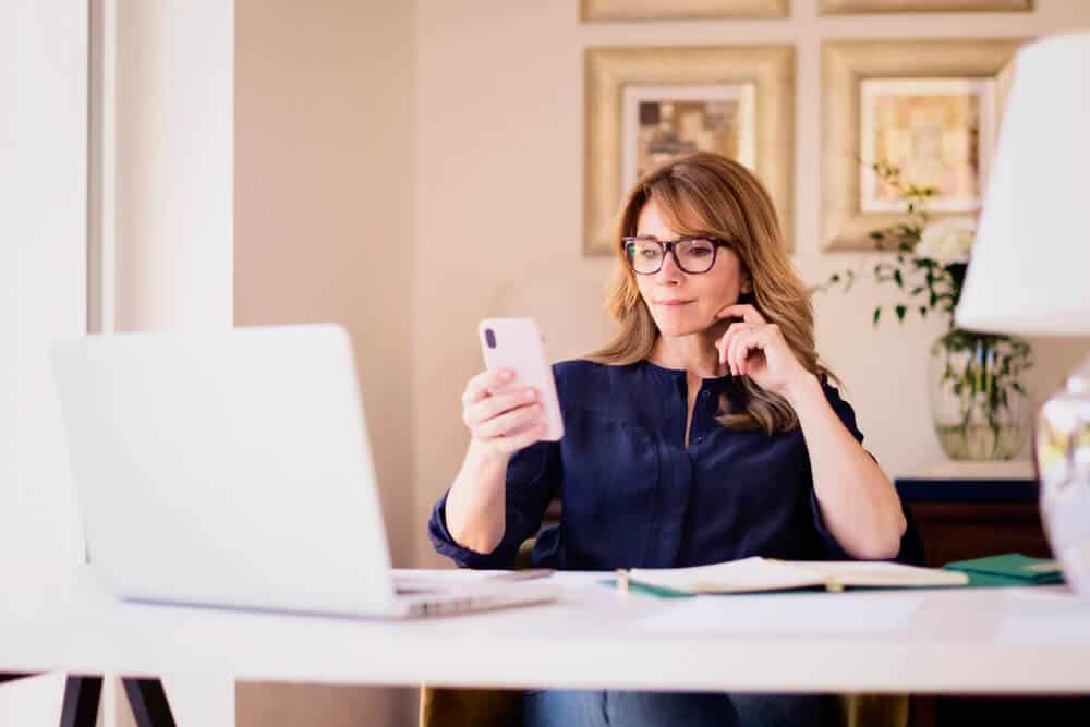 woman sitting at desk with laptop and text messaging