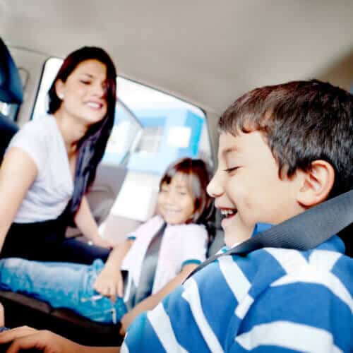 hispanic mother securing children in backseat of car