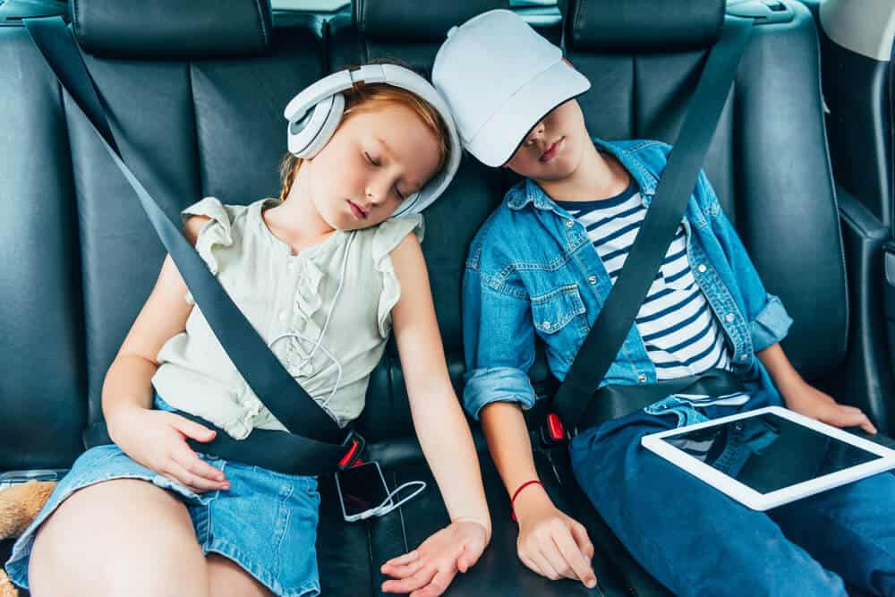 two young children asleep in backseat of car