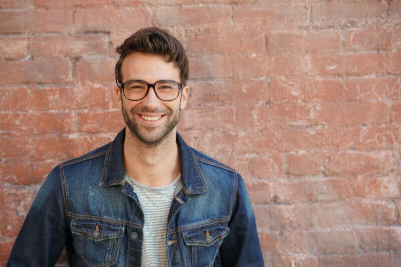Smiling,Trendy,Guy,With,Blue,Jeans,Jacket,And,Eyeglasses,Standing smiling Caucasian male