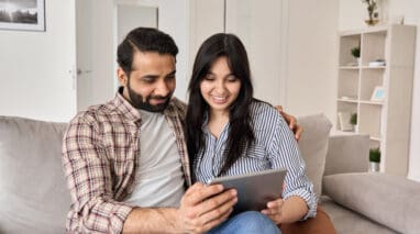 young indian couple researching life insurance policies on tablet