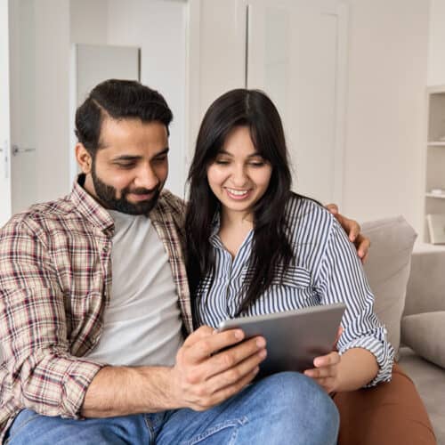 young indian couple researching life insurance policies on tablet