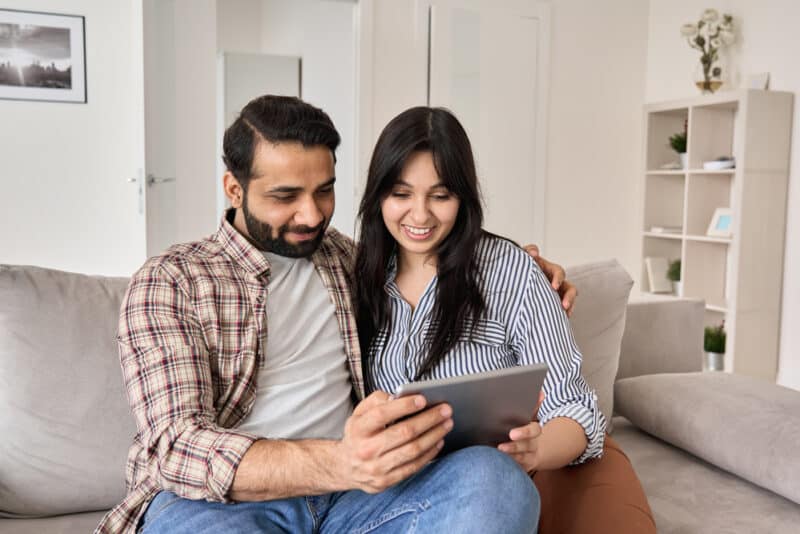 young indian couple researching life insurance policies on tablet