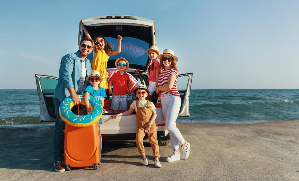 large family on beach near car