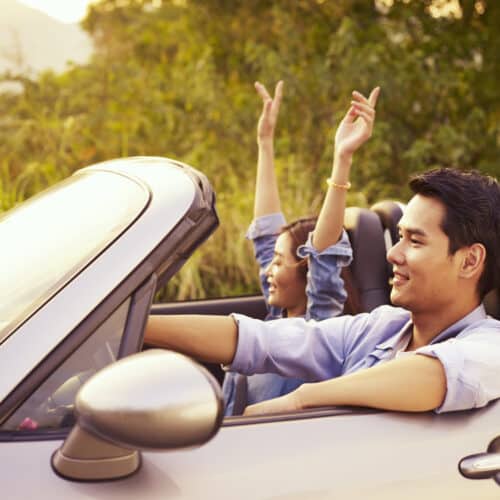 young asian couple driving with top down