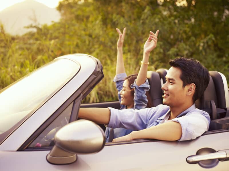 young asian couple driving with top down