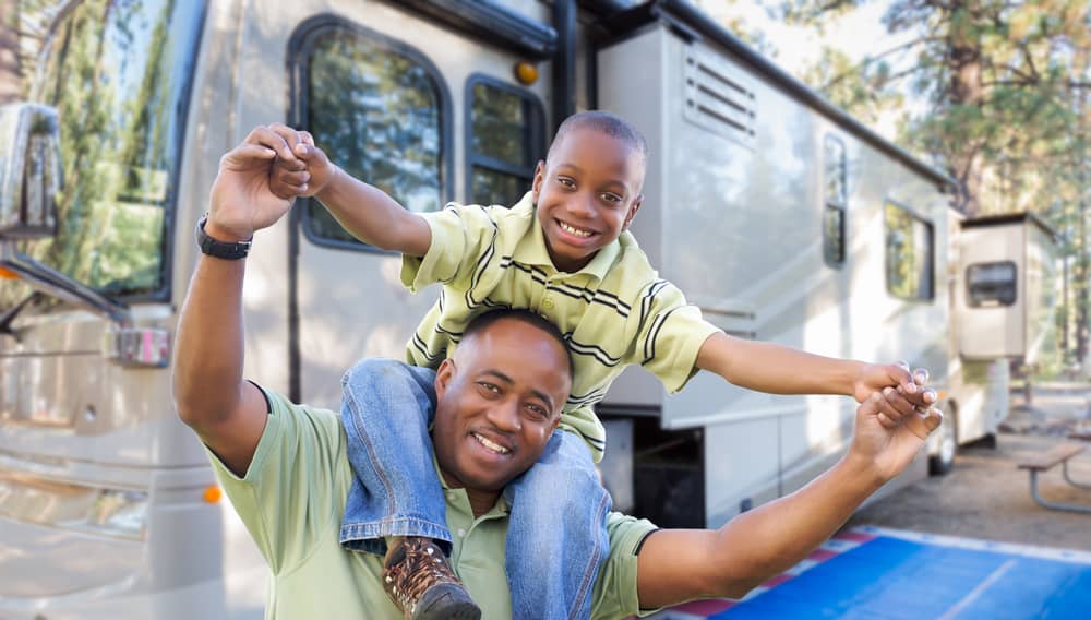 Father and son with RV in pine trees
