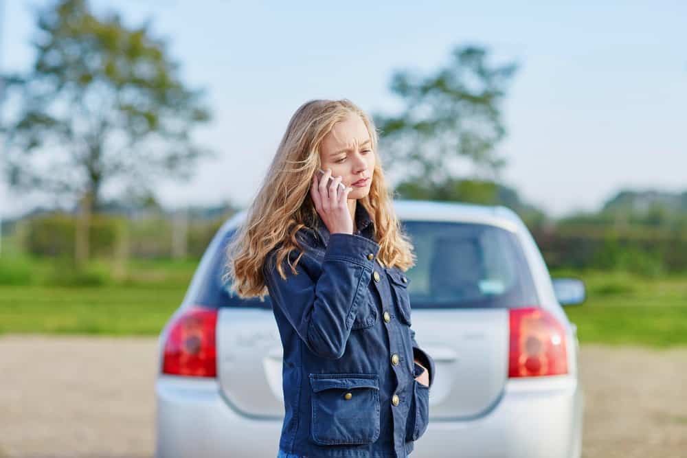 young woman on phone near car