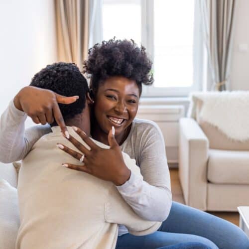 young couple getting engaged, woman smiling with hand up