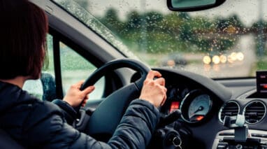 woman gripping steering wheel driving in rainy weather
