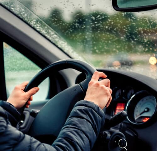 woman gripping steering wheel driving in rainy weather
