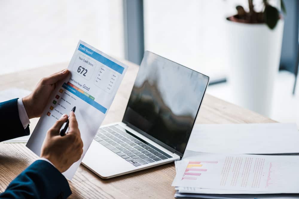 person going over credit report in front of laptop