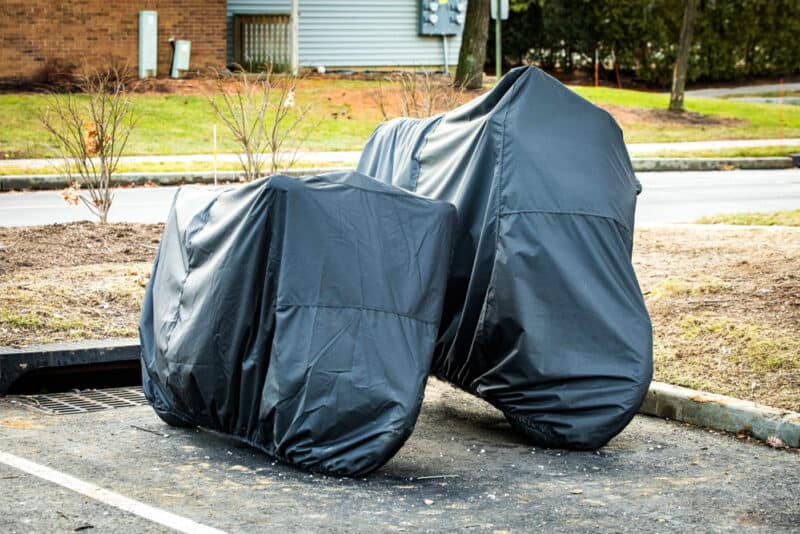 two motorcycle stored under cover in parking lot