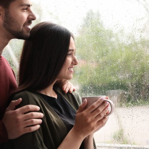 Young couple looks at a window at the rain in Washington