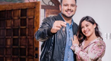 Young Hispanic couple shows off keys to new home
