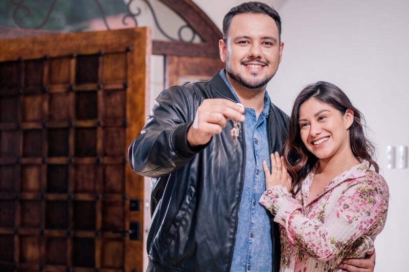 Young Hispanic couple shows off keys to new home