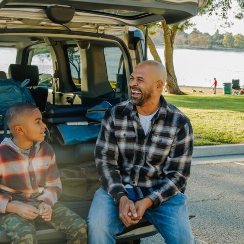 African-American father and son prepare to do some car camping by the lake