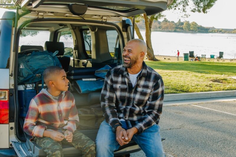 African-American father and son prepare to do some car camping by the lake
