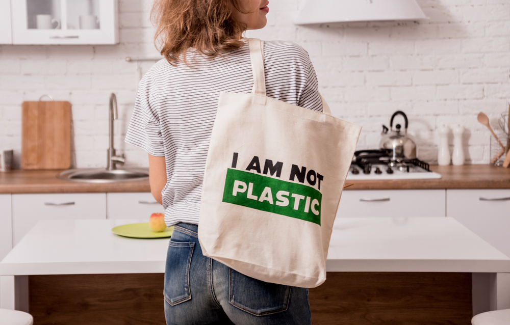 Picture of woman from behind with a reusable grocery bag over her shoulder