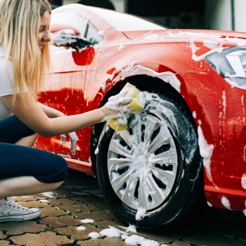 young woman washing her red car in washington
