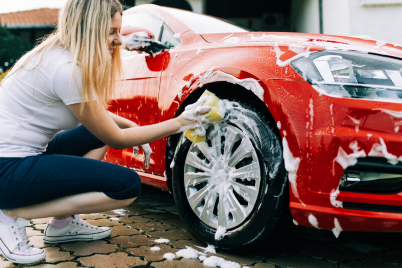 young woman washing her red car in washington