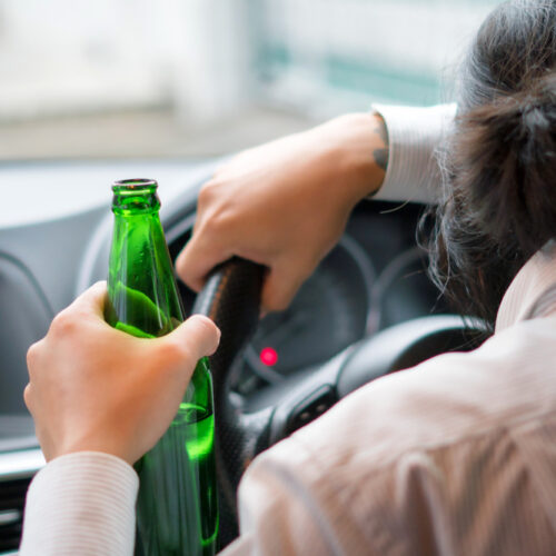 Young man drinks a beer while driving