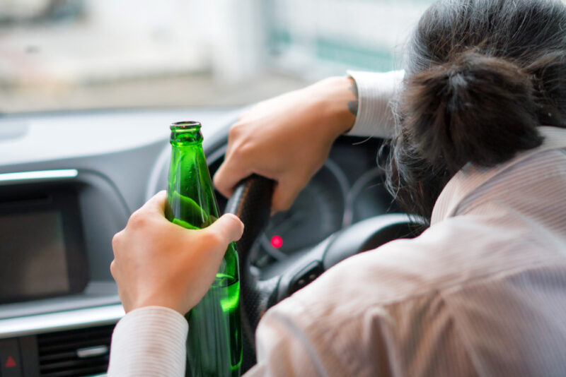 Young man drinks a beer while driving