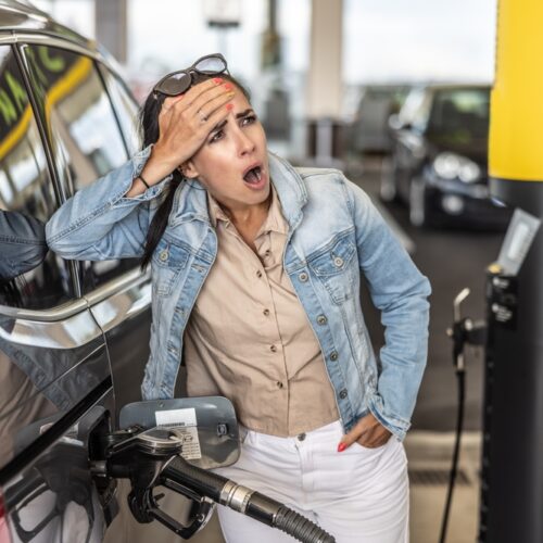 woman stares in horror at gas pump prices
