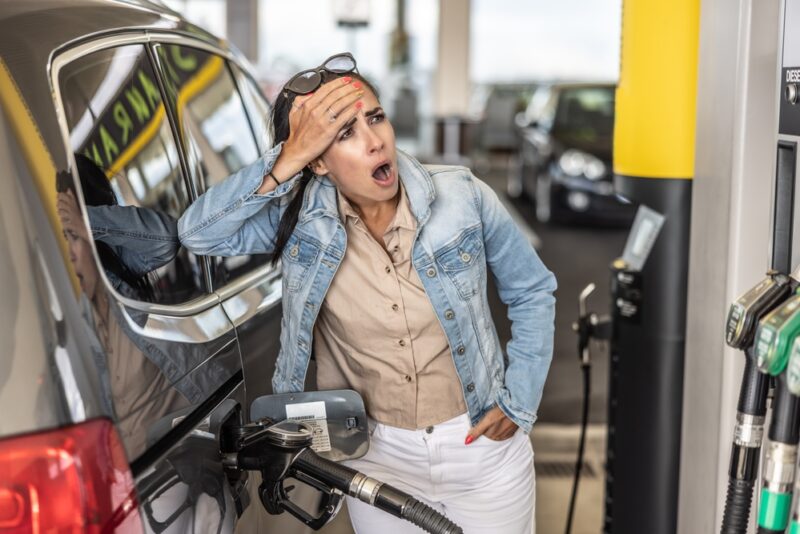 woman stares in horror at gas pump prices