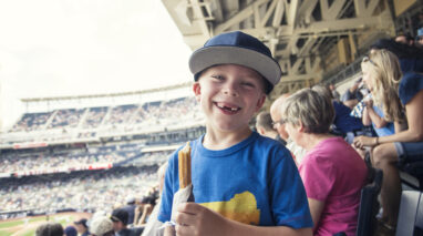 Snaggle-tooth kid happily enjoying a churro at the ball game