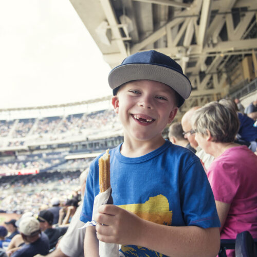Snaggle-tooth kid happily enjoying a churro at the ball game