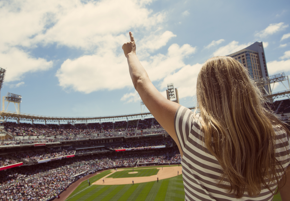 Back view of a woman raising her finger for #1 at a ballgame