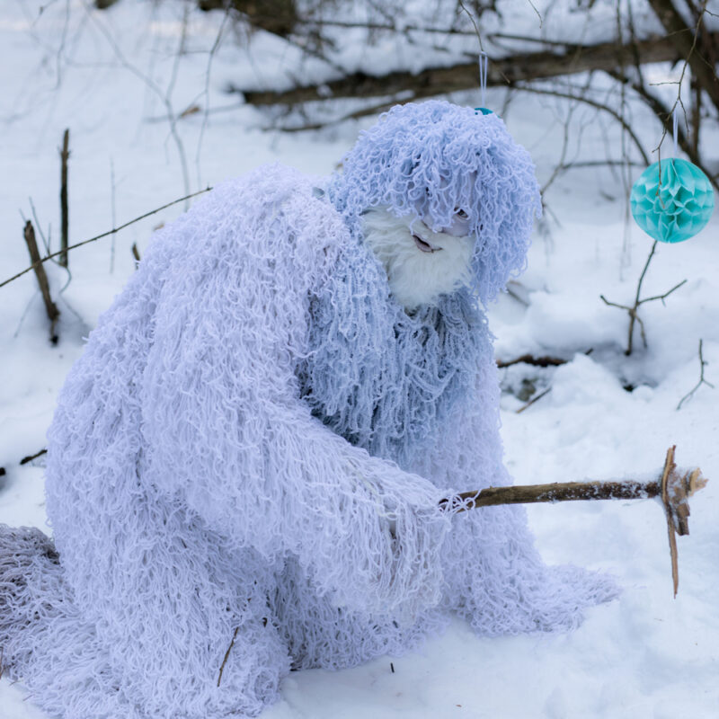 A man pretends to be Sasquatch in the snowy wilderness