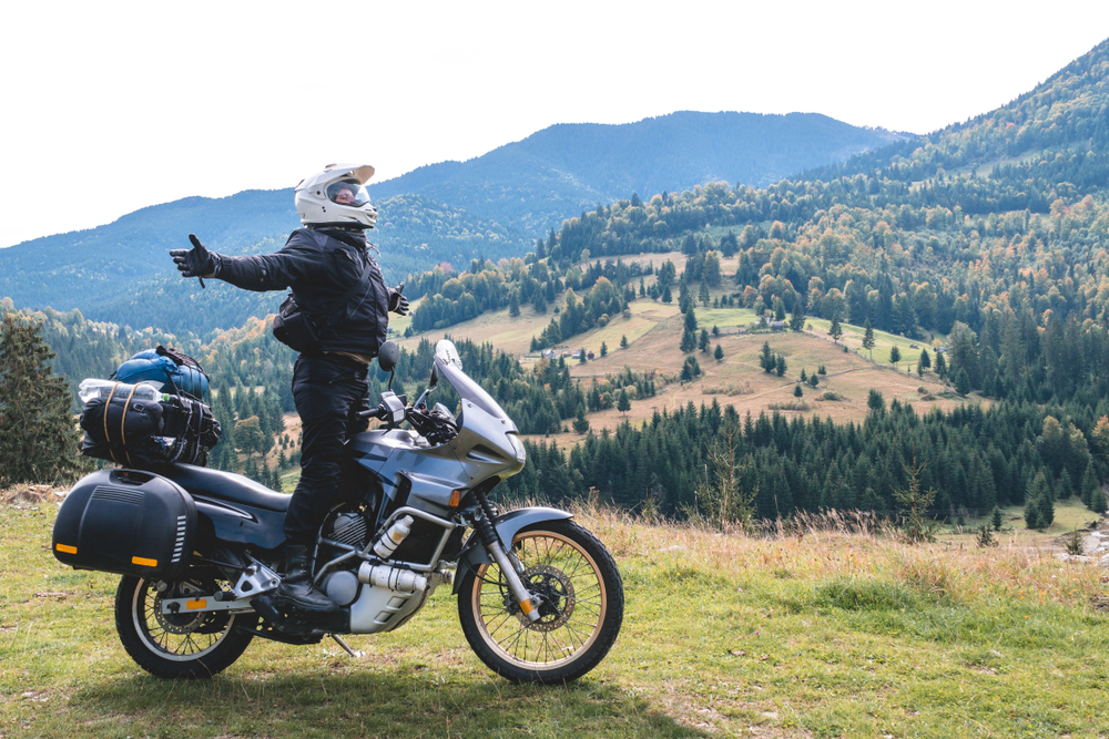 Motorcyclist showing enthusiasm for location by standing on pegs with arms outstretched