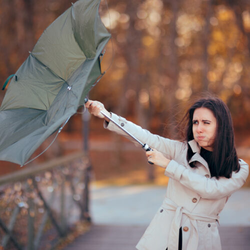 Business woman fights the wind while her umbrella turns inside out