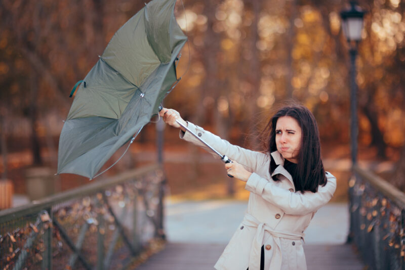 Business woman fights the wind while her umbrella turns inside out